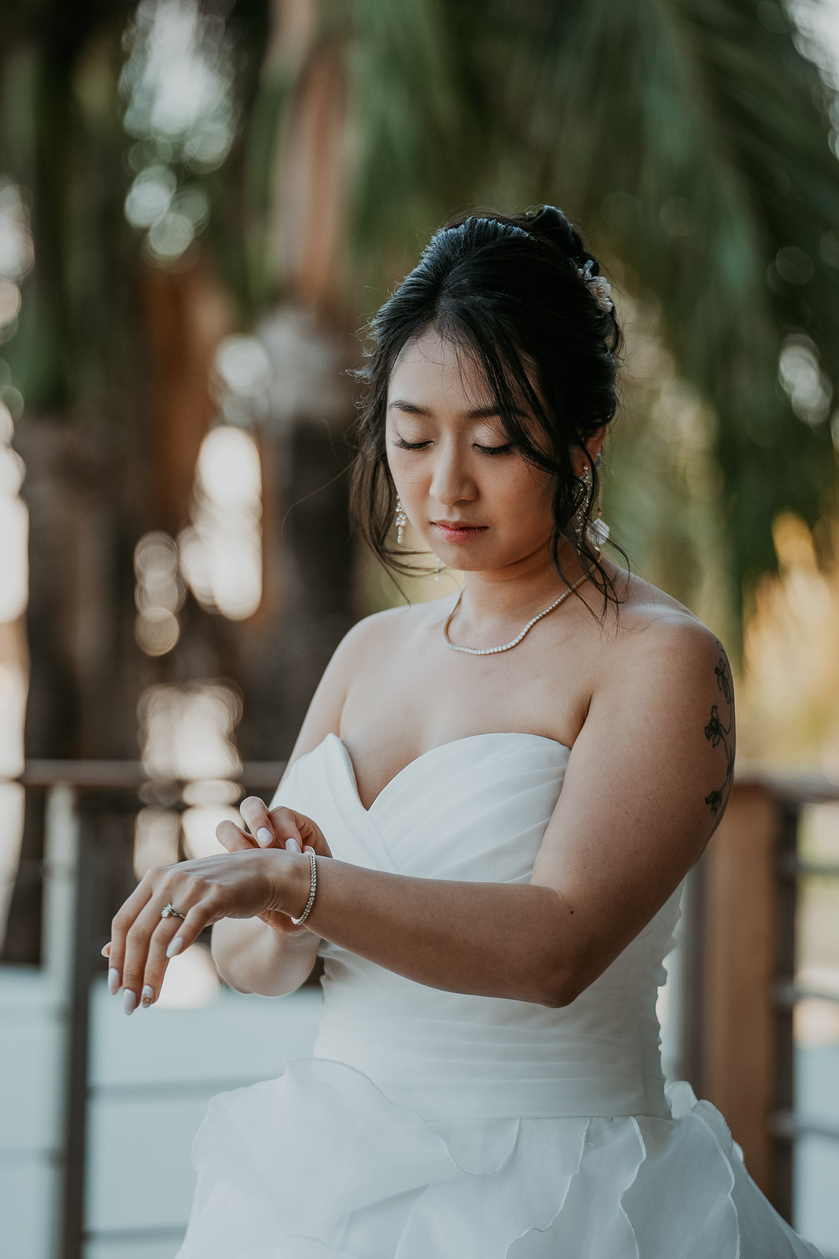 A quiet, unposed portrait of a bride adjusting jewelry.