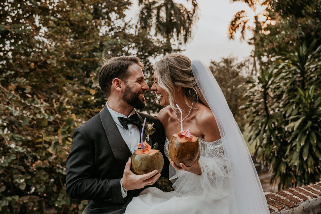 Playful wedding moment with couple sipping coconuts at Museo Casa Blanca.