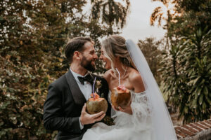 Playful wedding moment with couple sipping coconuts at Museo Casa Blanca.