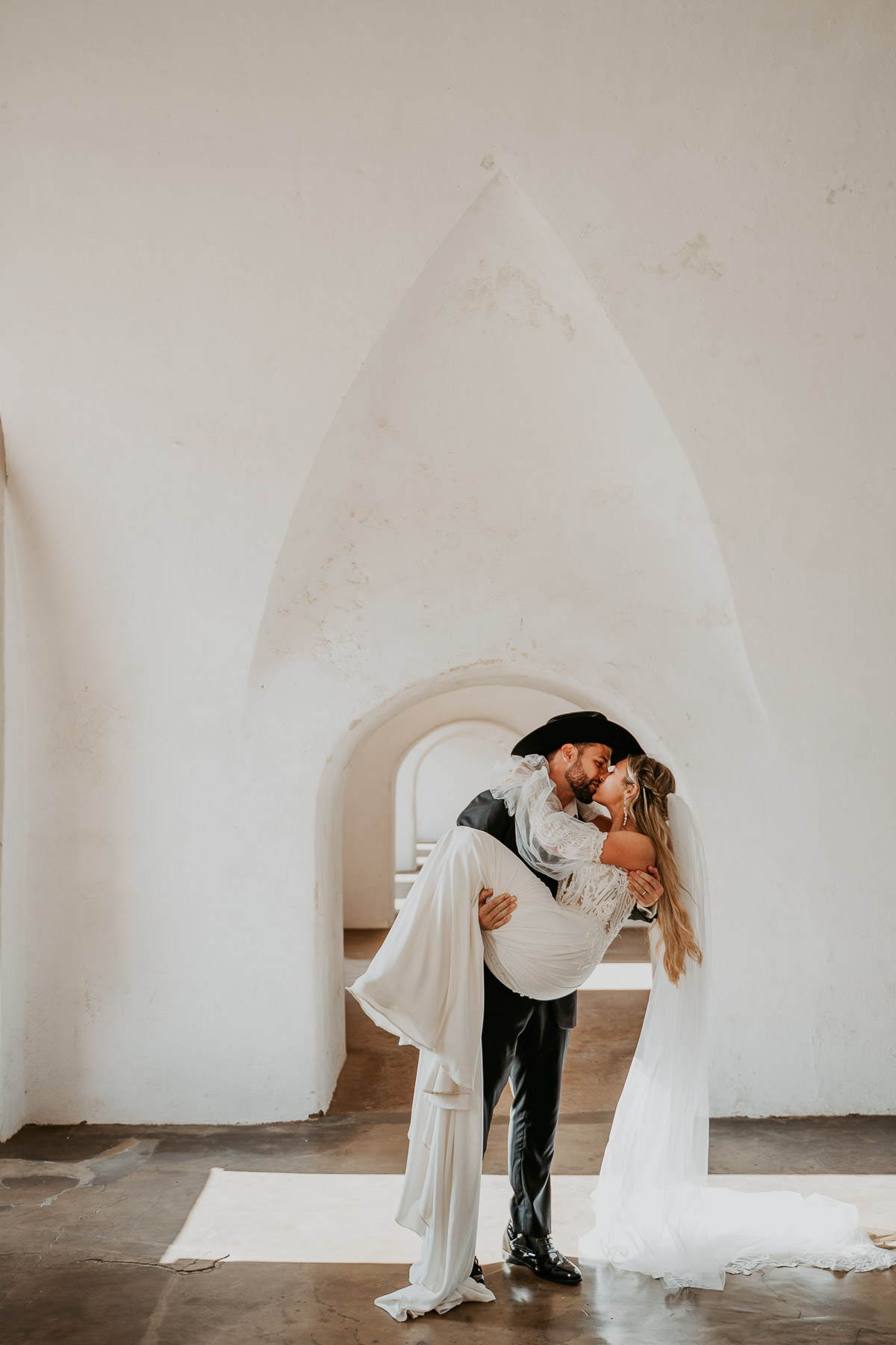 Romantic wedding portrait framed by white stone arch in Puerto Rico.