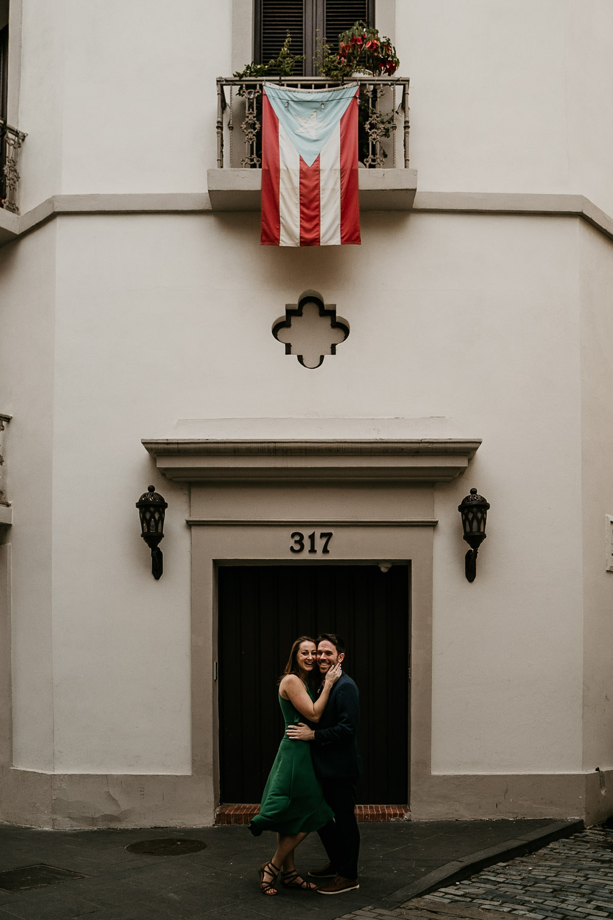 Couple with colonial building and Puertorrican flag during couples session at Old San Juan.