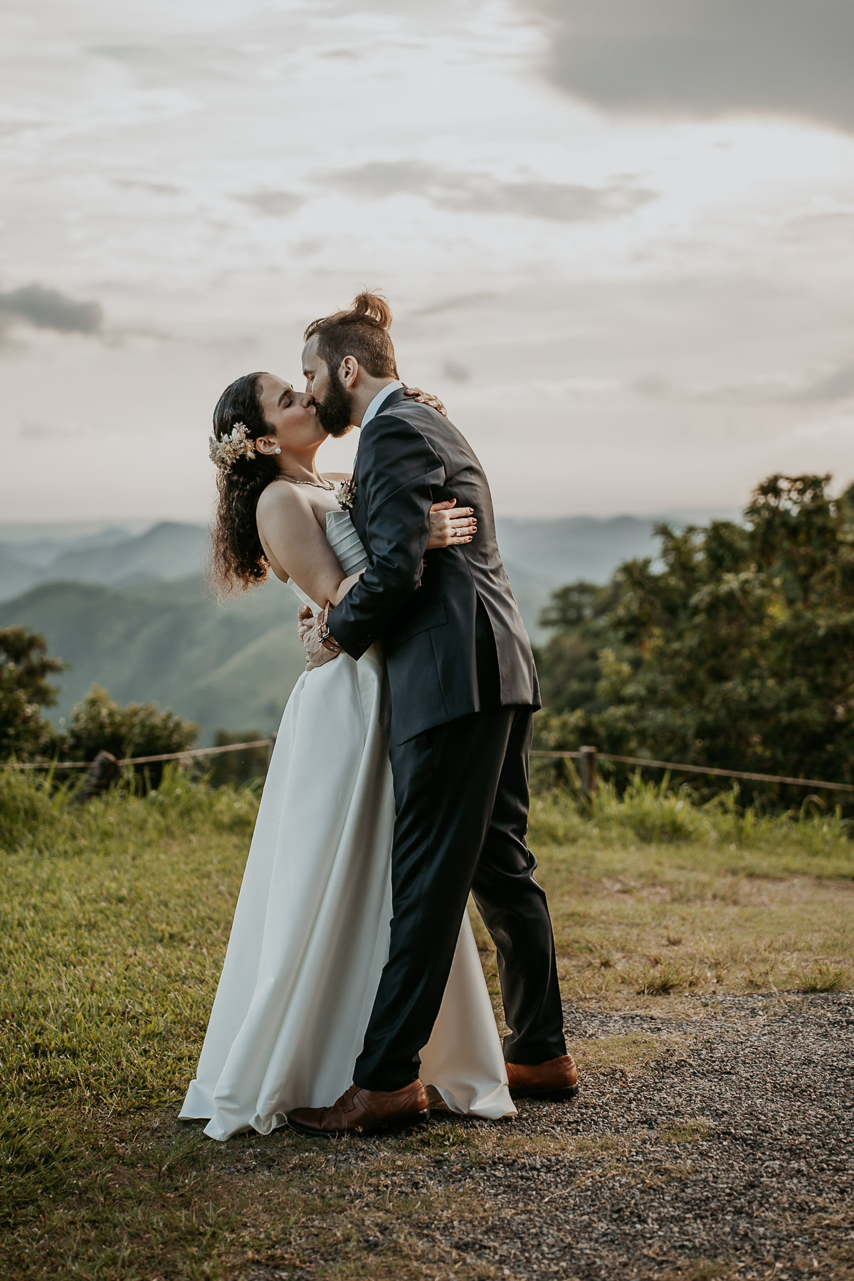 Couple sharing their first kiss during an intimate elopement ceremony in Cayey, Puerto Rico, with misty mountains as the backdrop.