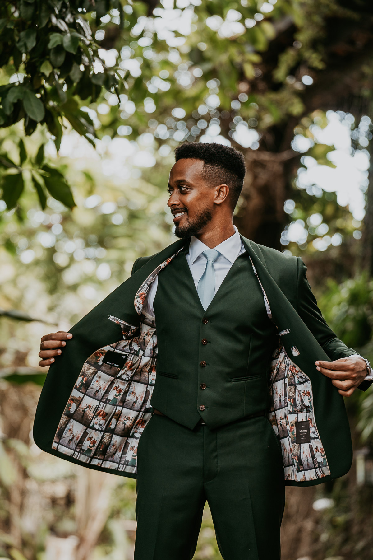 Groom showing off the interior of his wedding jacket decorated with pictures of the bride and him.