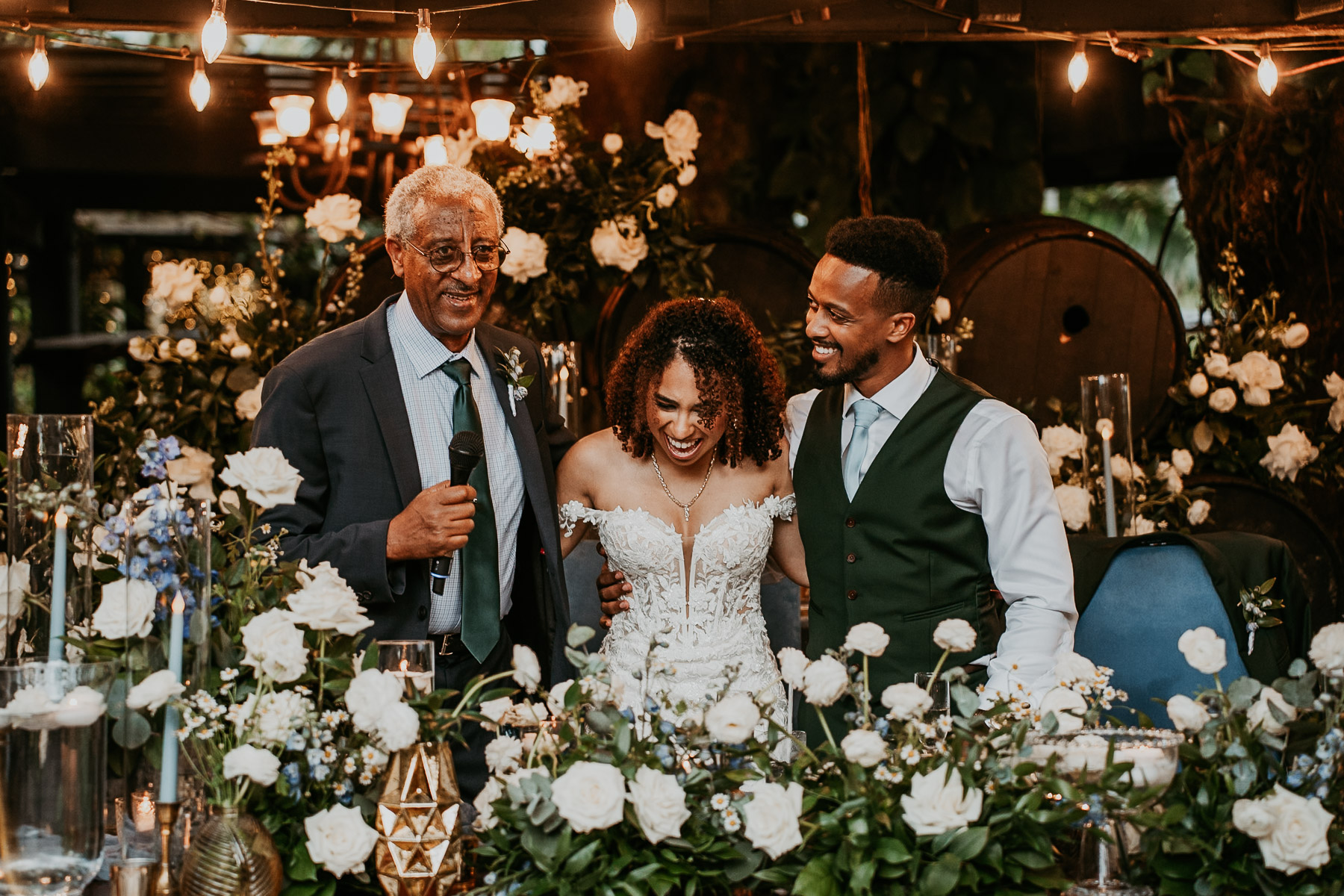 Bride and groom candid moment with parent during wedding toast.