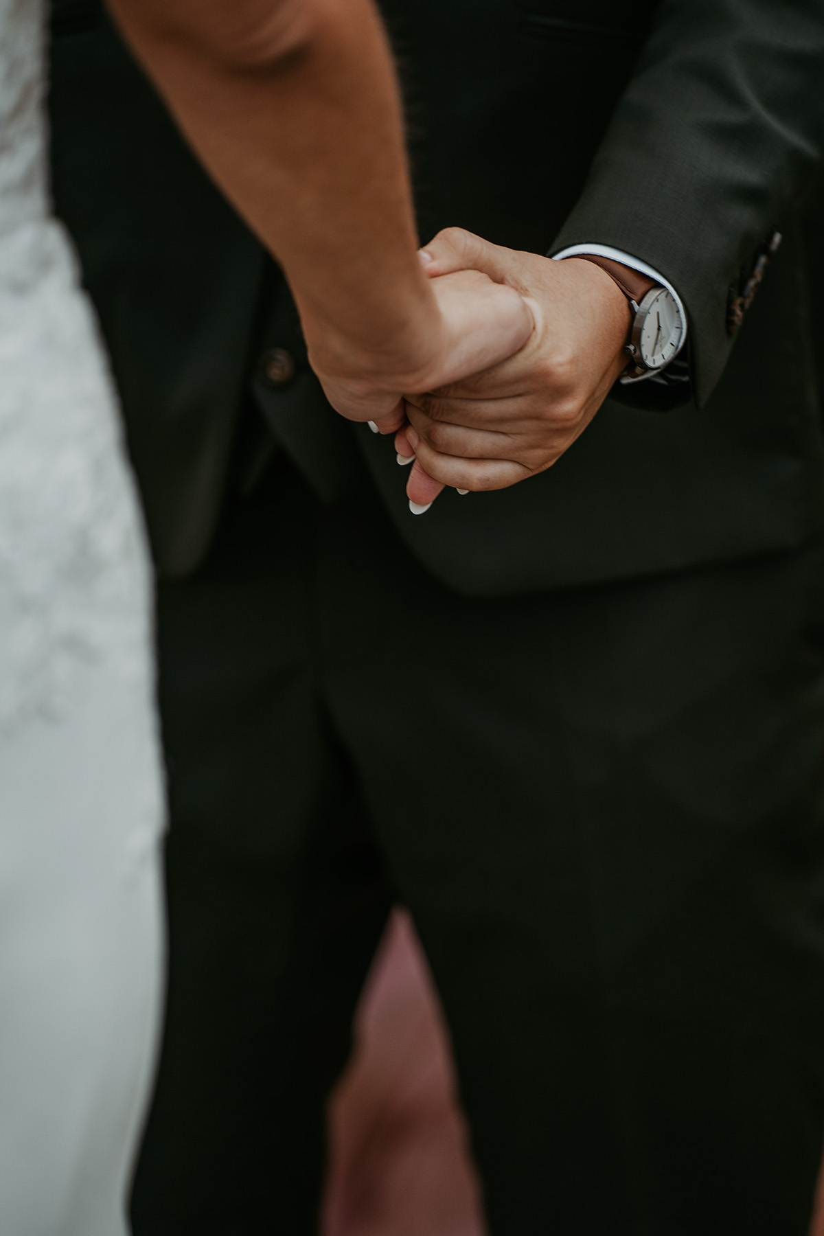 Detail shot of couple holding hands during wedding ceremony.