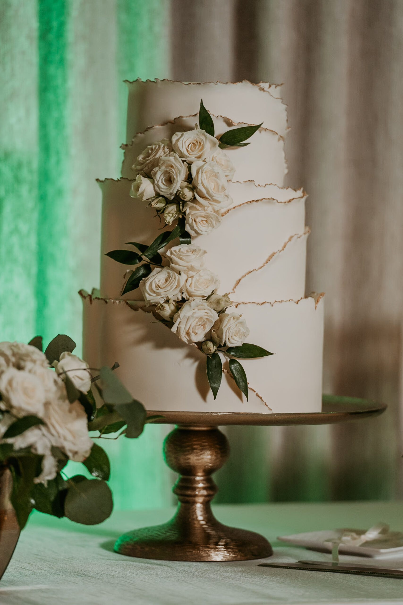 Chic wedding cake with gold accents and delicate flowers at Salon del Mar reception room