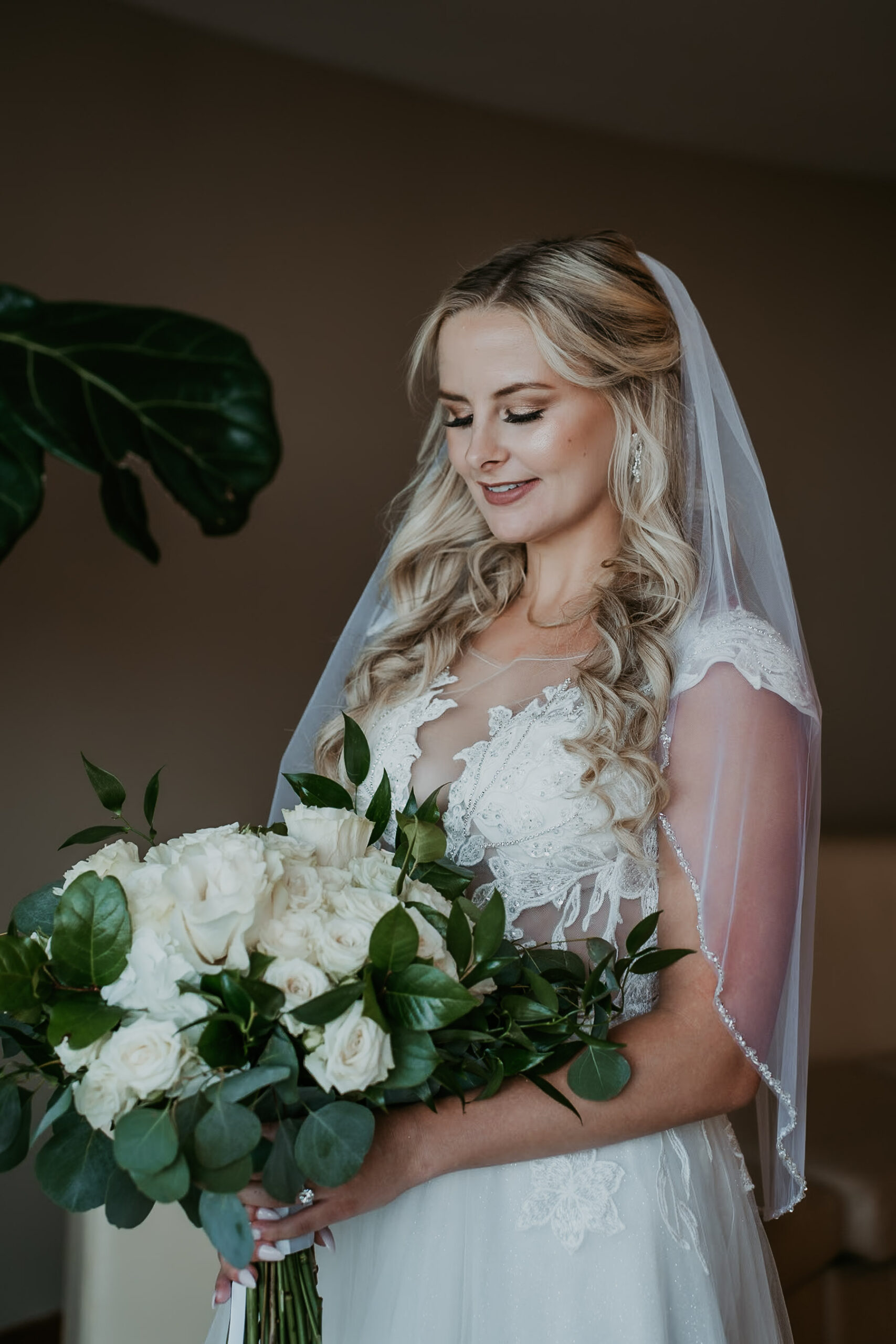 Bride looking at her bouquet of white flowers at Courtyard Marriot