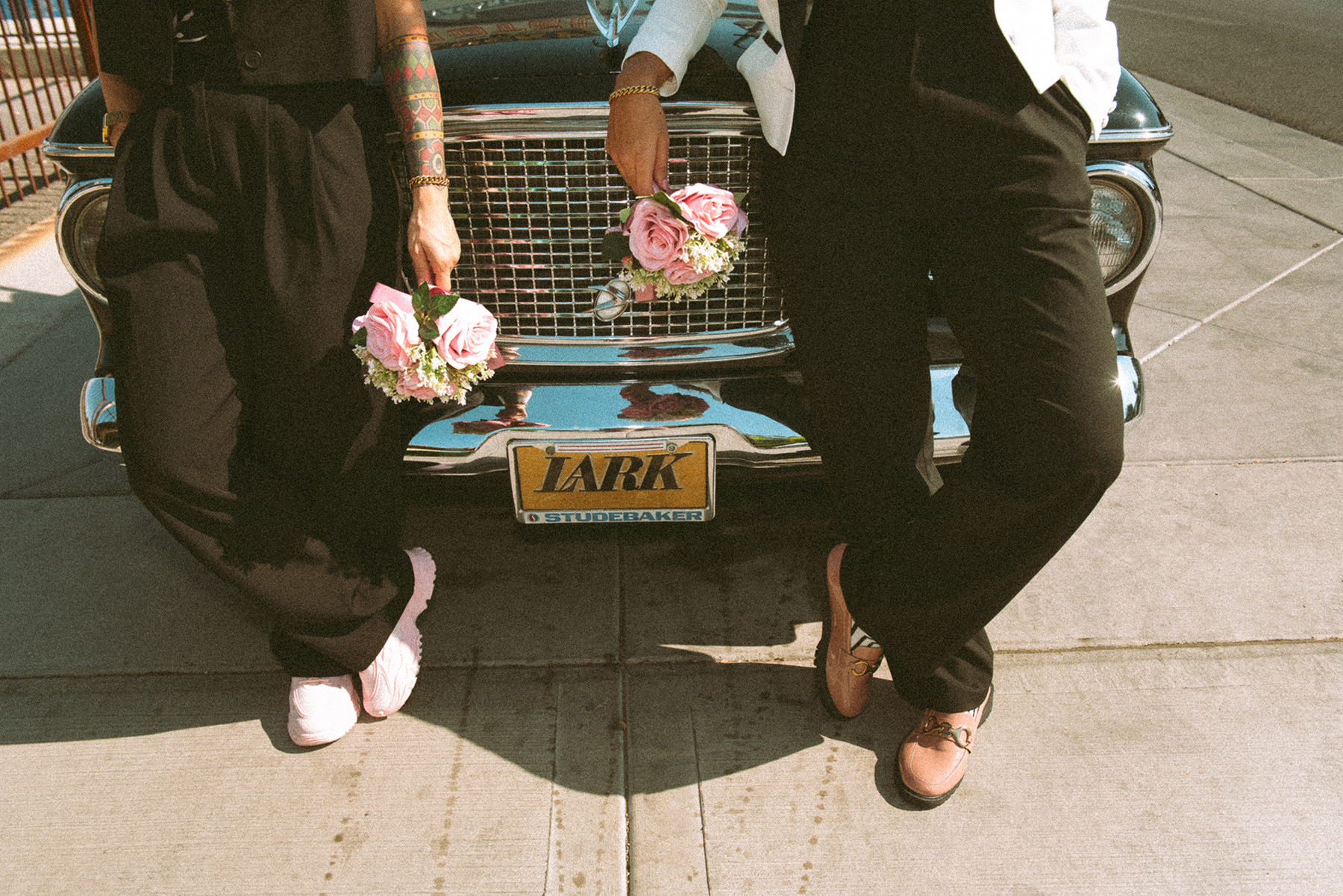 Lesbian maried couple posing in front of vintage car
