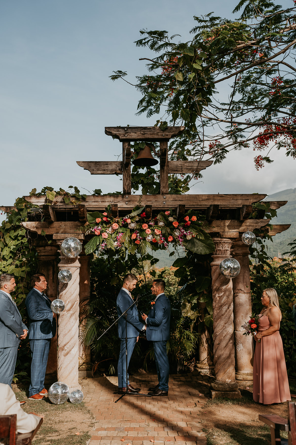 Couple at their LGBTQ+ wedding at Hacienda Siesta Alegre standing under vine-covered pergolas