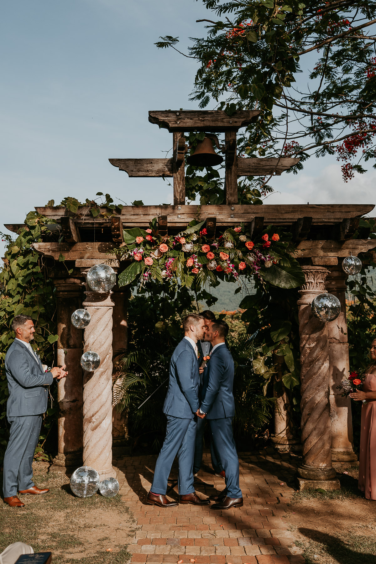 Couple at their LGBTQ+ wedding at Hacienda Siesta Alegre standing under vine-covered pergolas