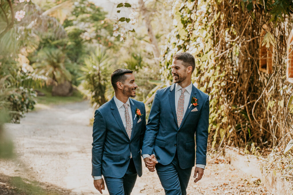 Grooms under archway of Hacienda Siesta Alegre LGBTQ+ wedding