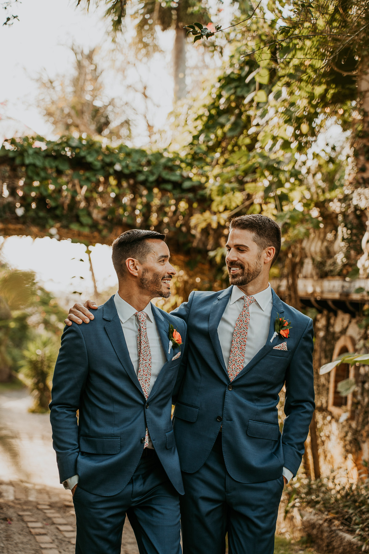 Grooms under archway of Hacienda Siesta Alegre LGBTQ+ wedding