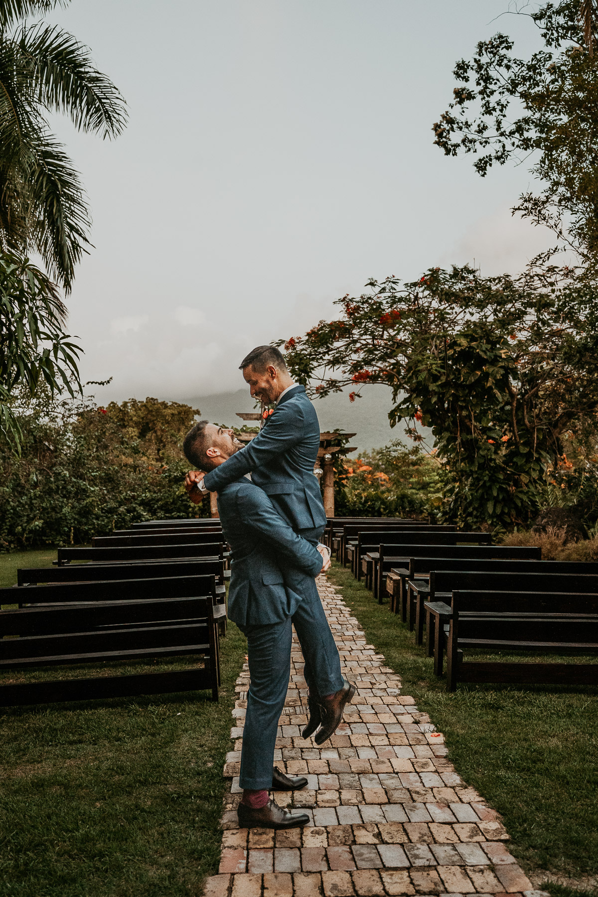 Grooms under archway of Hacienda Siesta Alegre LGBTQ+ wedding