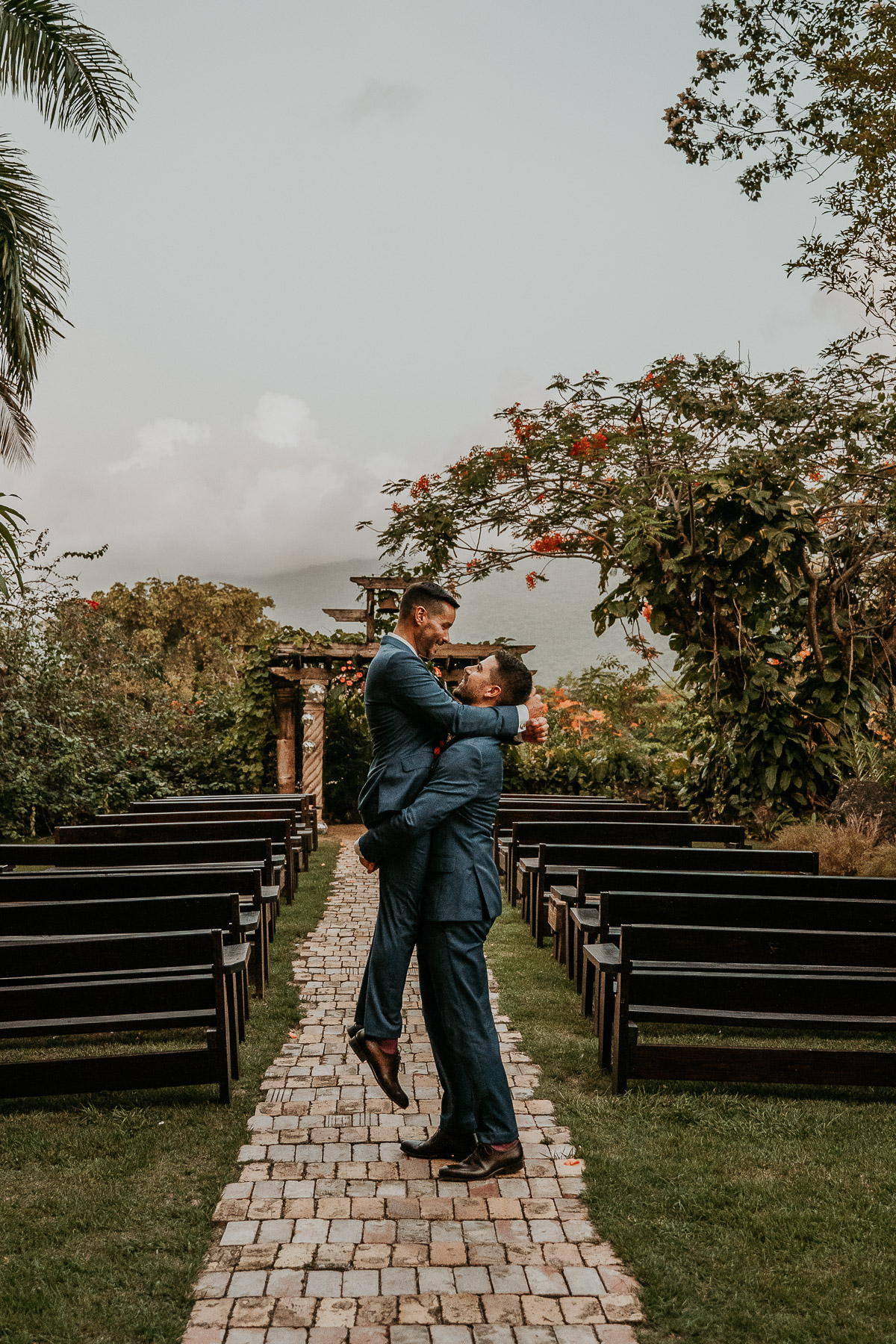 Grooms under archway of Hacienda Siesta Alegre LGBTQ+ wedding