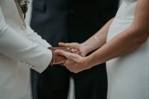 Interracial lesbian couple holding hands during wedding ceremony at Fairmont Hotel