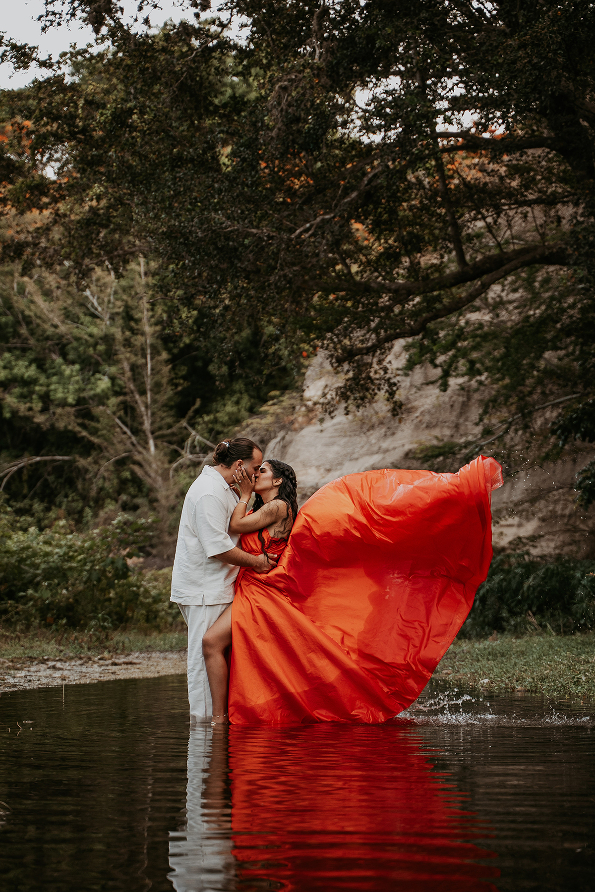 Couple kissing beside a river during an intimate Puerto Rico adventure engagement session