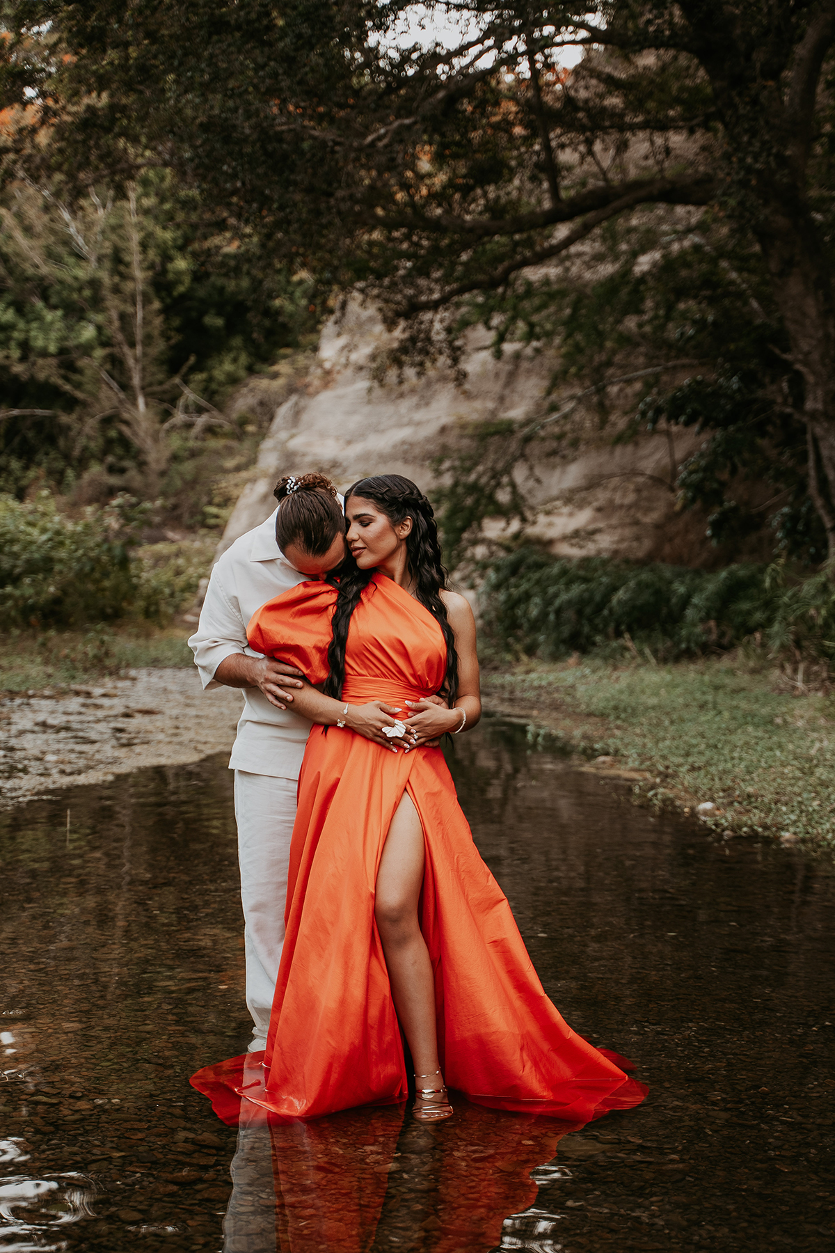 Couple embracing beside tropical vegetation during a candid Puerto Rico adventure engagement session