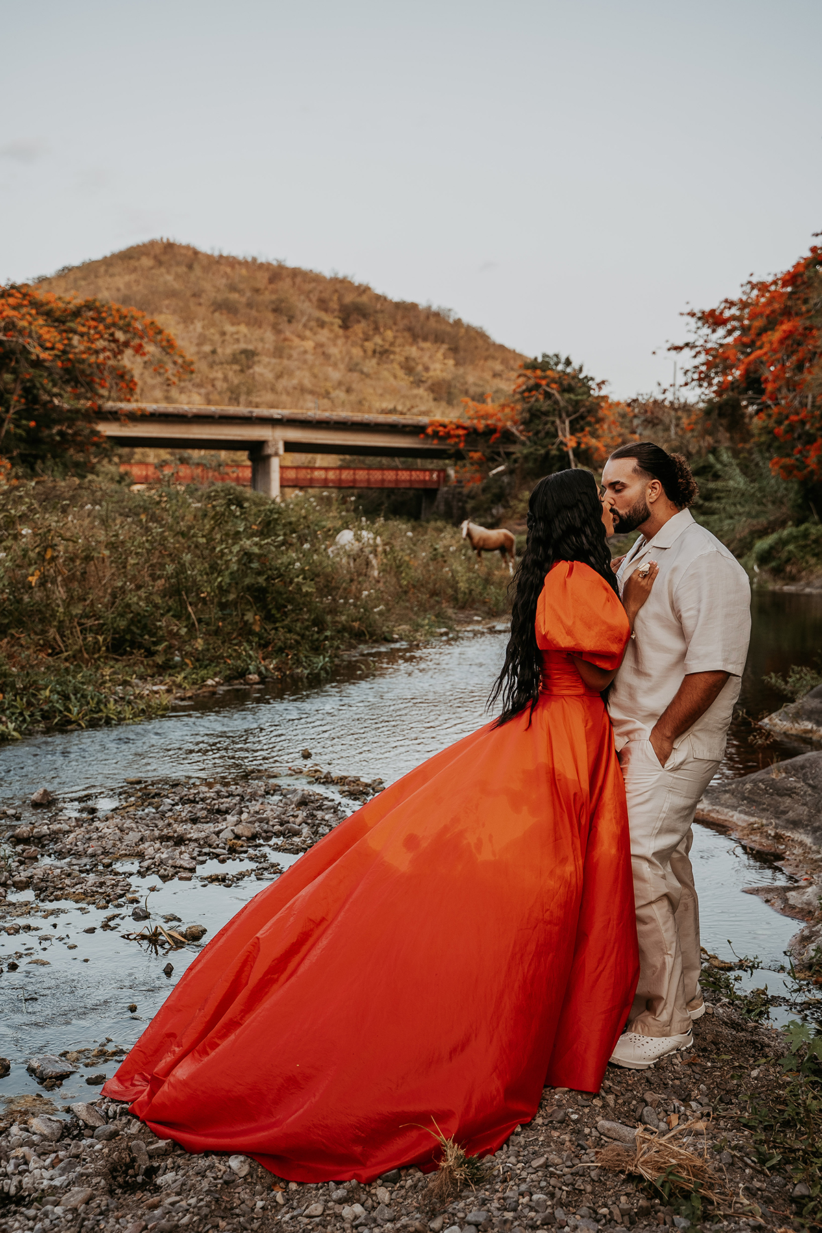 Couple beside a river with wild horses and tropical greenery during an off-the-beaten-path Puerto Rico photo session
