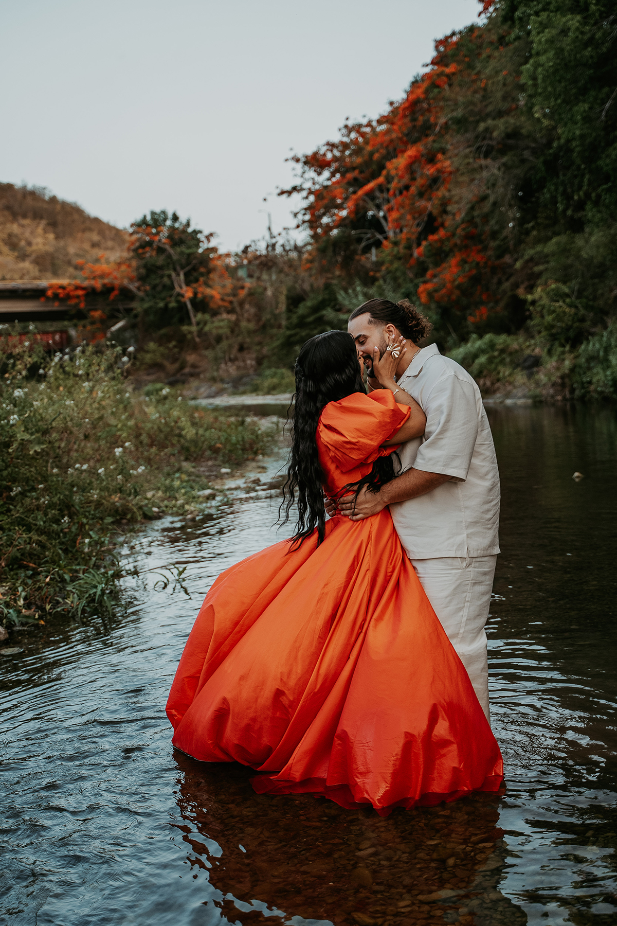 Couple kissing beside a river during an intimate Puerto Rico adventure engagement session