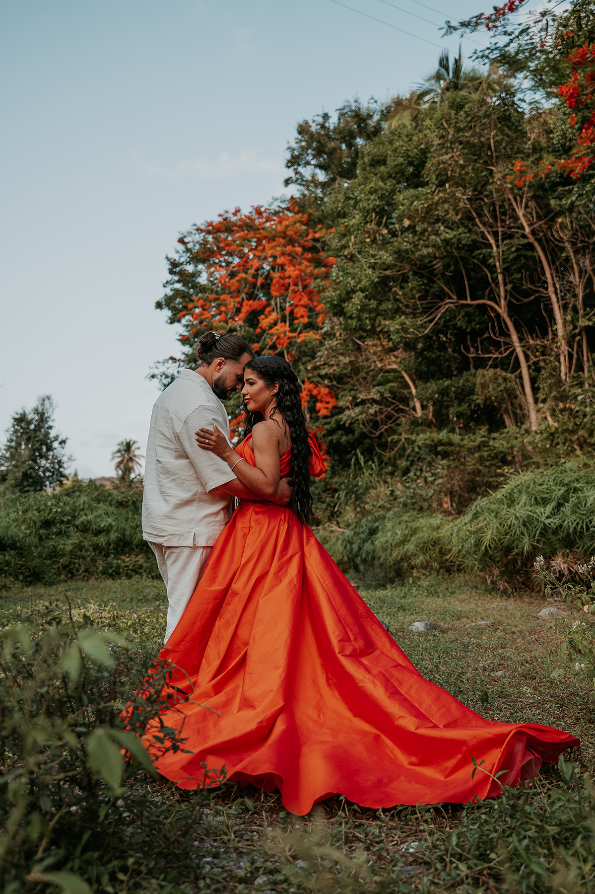 Couple embracing beside tropical vegetation during a candid Puerto Rico adventure engagement session