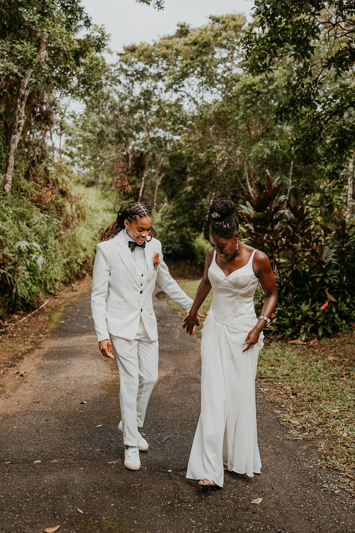 The couple walks hand in hand, surrounded by lush greenery.