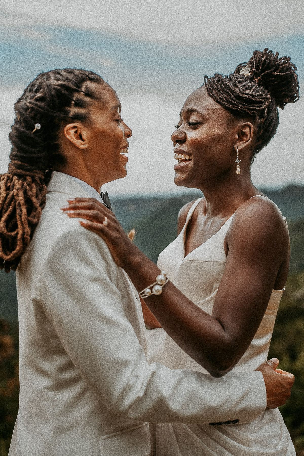 Two brides laughing together during their outdoor wedding photo session at a picturesque Airbnb.