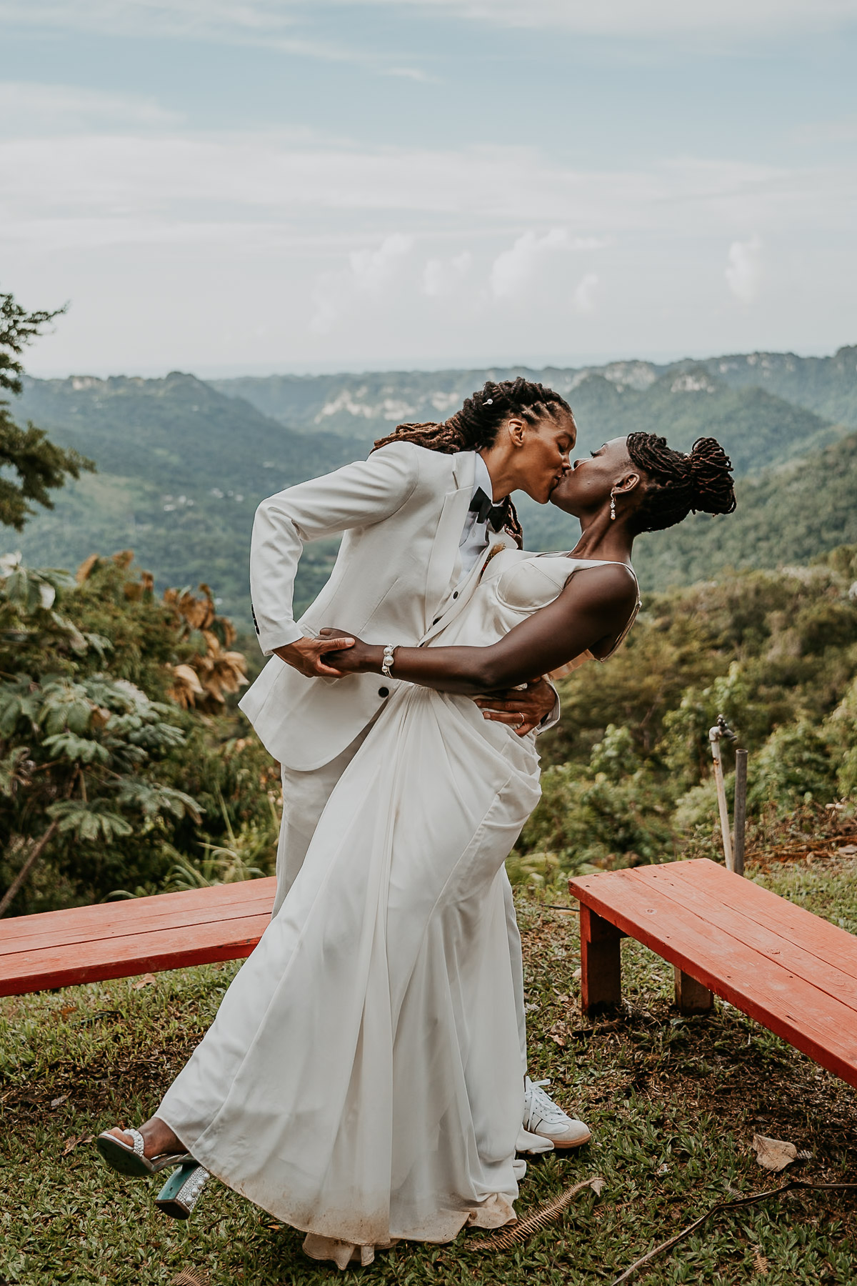 A romantic kiss between the brides, framed by breathtaking mountain views at their Airbnb venue.