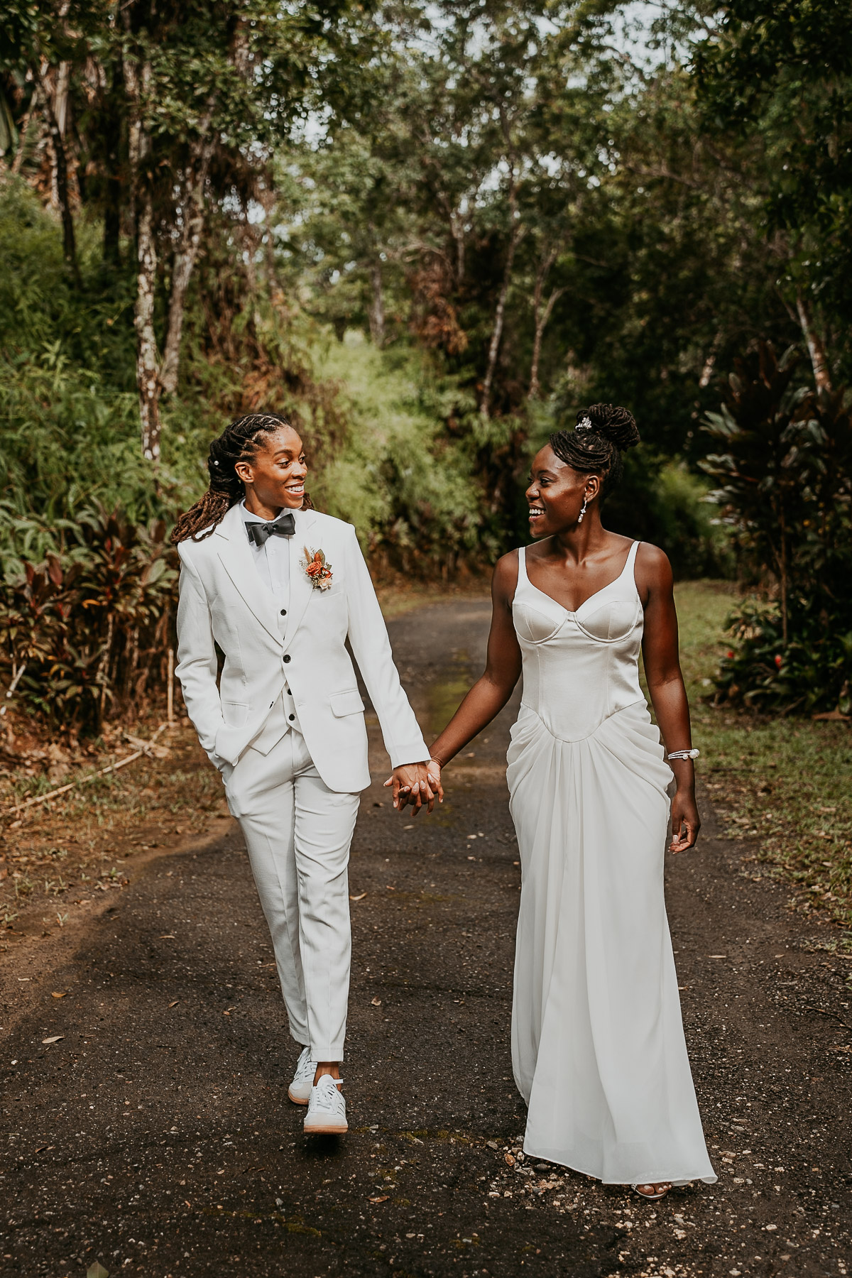 The couple walks hand in hand, surrounded by lush greenery.