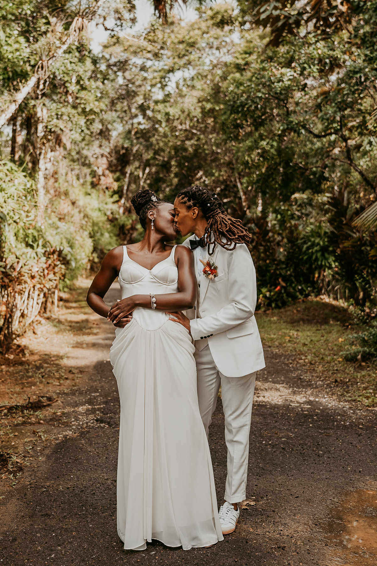 Two brides kiss at their Airbnb micro wedding in Puerto Rico surrounded by lush greenery.