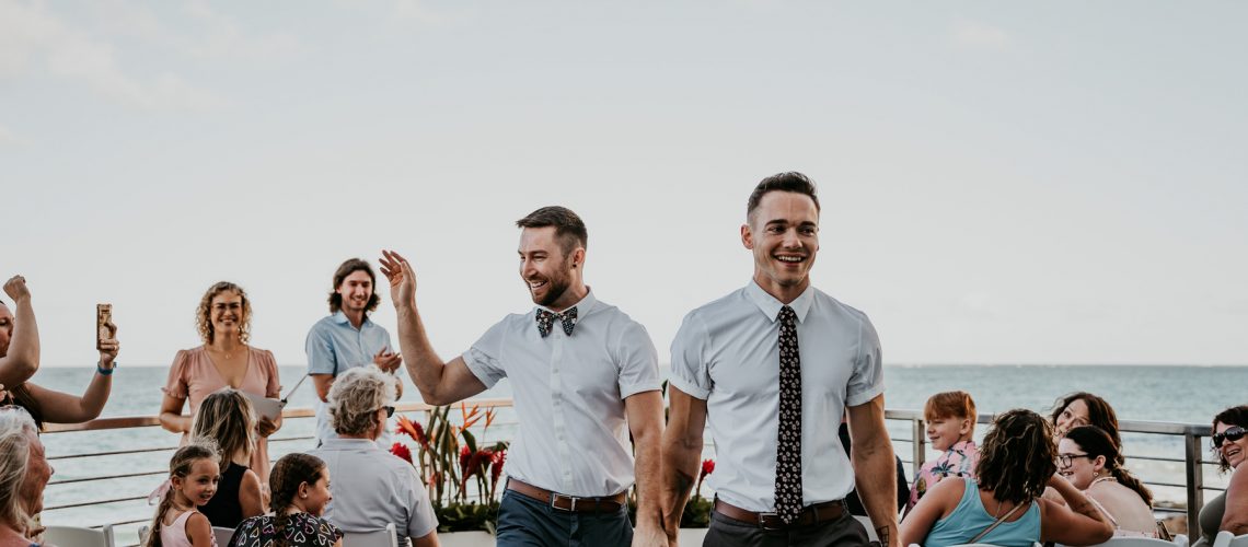 Gay couple celebrating their micro wedding at at beachfront venue.