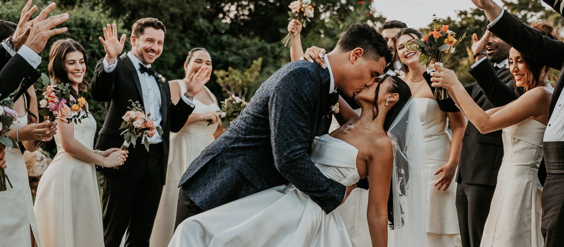 Bride and groom kiss at Hacienda Campo Rico surrounded by friends.