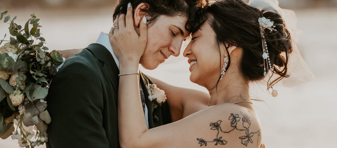 Candid photo of lesbian couple embracing each other on the coastline.